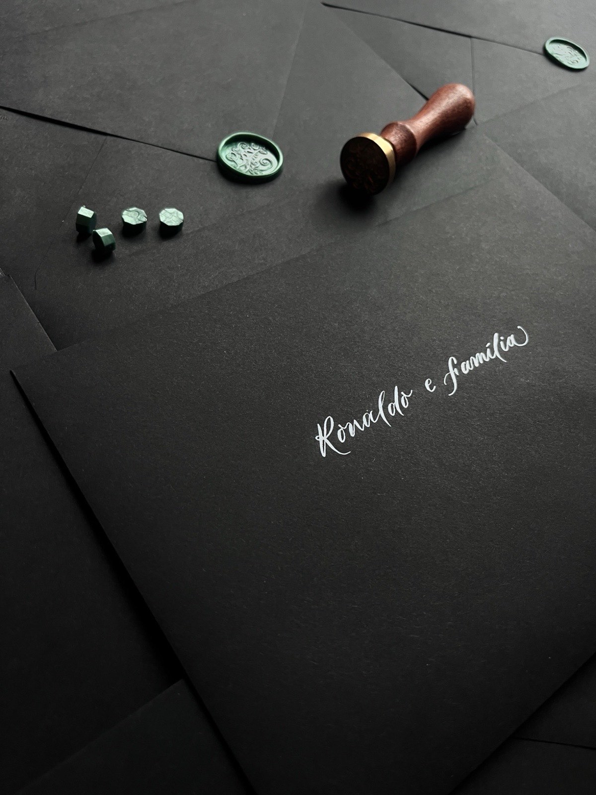 Hand-lettered wedding envelope suite in white calligraphy on black paper with green wax seals